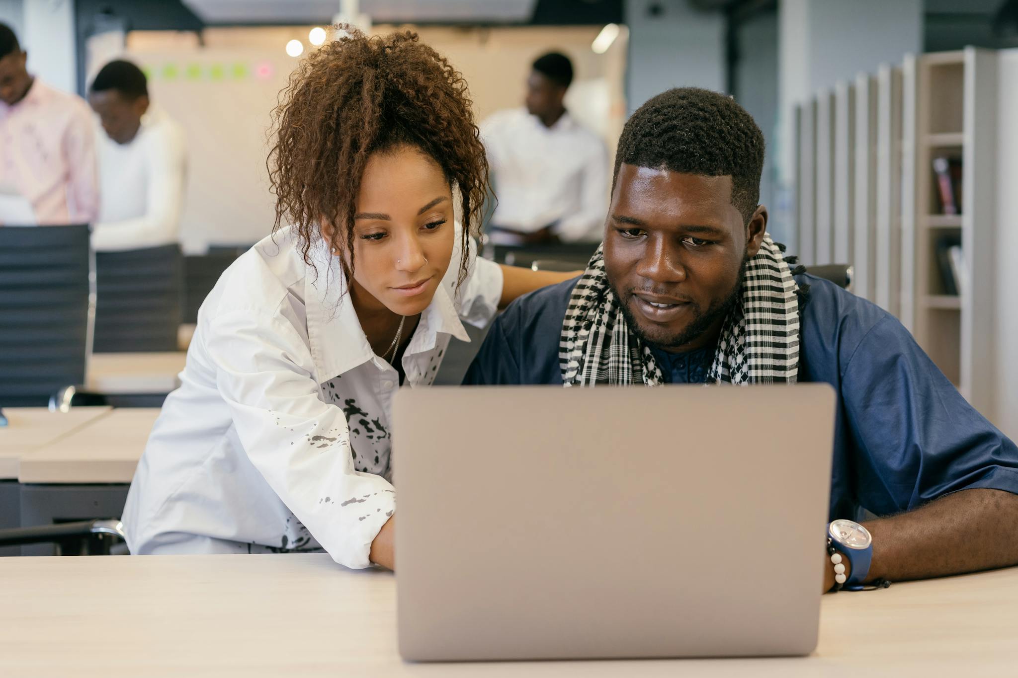 Two colleagues working together on a laptop in a contemporary office environment.